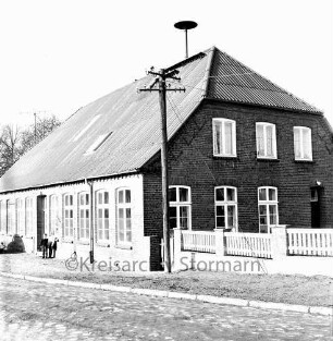 Schlamersdorf: Dorfstraße mit Kopfsteinpflaster: Volksschule: rechts Zaun: davor Strommast: links Kind