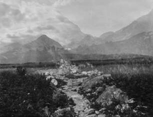 Am Bach : Blick über eine Wiese mit Bach. Im Hintergrund hohes Gebirge