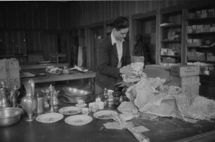 Ein Mitarbeiter des Collecting Points Marburg beim Auspacken von Zinnarbeiten, Porzellan und Gläsern im Hessischen Staatsarchiv