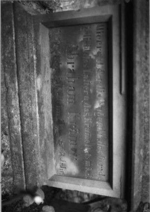 Grabstein 16 (Index: 99804463) Material: Sandstein Zustand: stark verwittert und abgeblättert Maße HxBxT: 176x63x32 cm Beschreibung: ädikulaartige Stele mit Halbsäulen, getreppter Sockel, Abschluß mit Zinnenaufsatz, Schriftfeld mit Maßwerk Symbolik: stilisierte Blätter, Maßwerk Besonderheit: kulturhistorisch wertvoll / künstl.-formale Gründe (Ornamentik, Form): Grabstein 16B (Detailaufnahme 1)