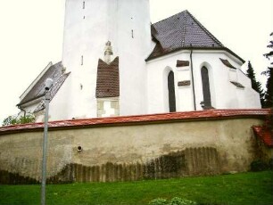 Ansicht von Südosten mit Kirche (Kirchturm im Kern Romanisch-Strebepfeiler Gotisch angefügt - Chor Neubau 14 Jh) über Kirchhofmauer (Wehrgang mit Steinbrüstung im 18 Jh abgetragen)