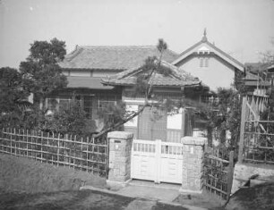 Japanisches Haus mit europäischem Anbau : Japanisches Haus mit europäischem Anbau. Ansicht mit geschlossenem Eingangstor und Garten