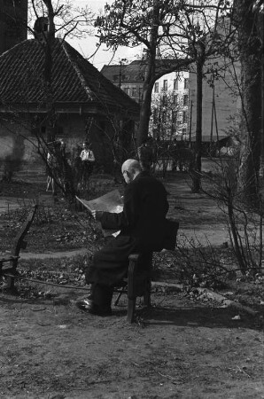 Berlin-Wilmersdorf. Kaiserplatz. Zeitungslesender Mann auf einer kriegszerstörten Sitzbank