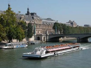 Hauptgebäude des Louvre-Museums mit Ausflugsschiff auf der Seine