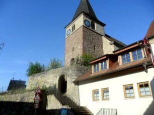 Ansicht von Nordosten mit Kirche (Chorturm mit Schlitzscharten) über Kirchhofmauer mit Torbogen
