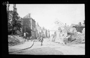 Nicht identifizierbare Ortschaft in der Umgebung von Origny (=Origny-Sainte-Benoite, Dep. Aisne, Frankreich): Straße mit einer Gebäuderuine am vorderen Eck