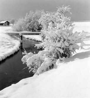 Winterbilder. Bachlauf mit Brücke in verschneiter Landschaft