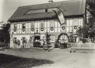 Seifhennersdorf (obersorbisch Wodowe Hendrichecy). Wohnhaus mit Fahne und Schmuck zum Sängerfest. Straßenansicht