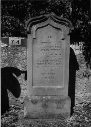 Grabstein 74 (Index: 100086538) Material: Sandstein Zustand: leicht verwittert Maße HxBxT: 174x62x16 cm Beschreibung: Stele, getreppter Sockel, Kielbogenabschluß mit Verdachung: Grabstein 74