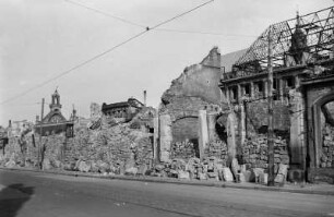 Blick über Gebäudereste und gestapelte Steine gegen Ruine der Reformierten Kirche und Neues Rathaus