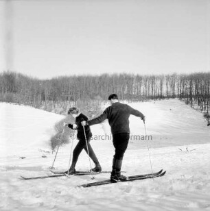 Kneeden: Hänge am Forst: vorn Mann und Frau auf Skiern: hinten Wald: Winter