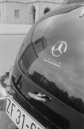 Im Heck eines Mercedes spiegelt sich ein Hochhaus