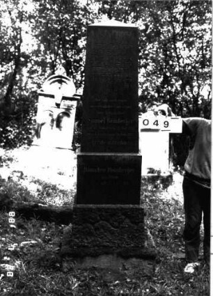 Grabstein 49 (Index: 100101229) Material: Granit Zustand: gut Maße HxBxT: 207x53x30 cm Beschreibung: Obelisk, getreppter Sockel Besonderheit: kulturhistorisch wertvoll / hist.-wiss. Gründe (Gemeindestellung); - Doppelgrab für Eheleute: Grabstein 49