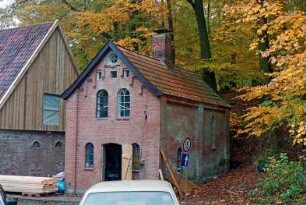 Nütschau: Schloßstraße 44: gegenüber von ehemaliger Kornwassermühle: links Pferdestall [angeschnitten], rechts Backhaus: Restaurierung: Erneuerung von Tür, Verbretterung an Giebel: Stapel mit Holzbrettern
