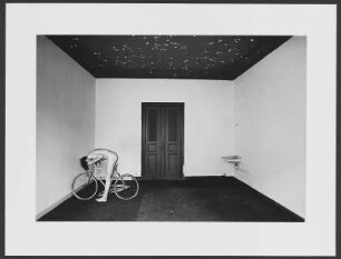 Fahrrad : Nackter Fahrradfahrer in einem kahlen Zimmer mit dunkler Decke