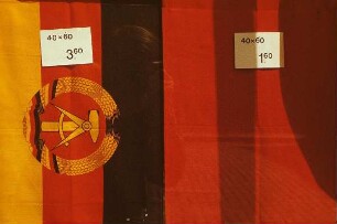 DDR. In einem Laden ausgepreiste Staatsfahne der DDR (3,60 Mark) und rote Arbeiterfahne (1,60 Mark)
