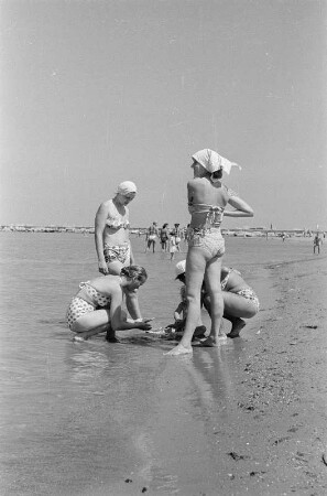 Eforie. Vier junge Frauen spielen mit einem kleinen Kind im flachen Wasser am Strand am Schwarzen Meer