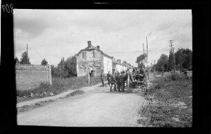 Nicht identifizierbare Ortschaft in der Umgebung von Origny (=Origny-Sainte-Benoite, Dep. Aisne, Frankreich): Soldaten mit Feldmützen auf einer Ortsstraße neben einem Leiterwagen (Rückansicht, Distanzaufnahme)