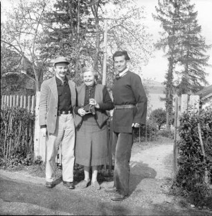Keine Beschreibung [zwei Männer mit älterer Dame vor Haus am Bergsee]