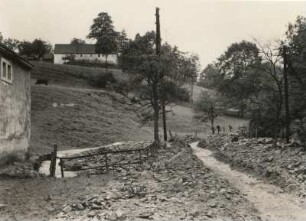 Gottleubatal. Von Schotter völlig verschüttete Straße nach Hartmannsbach mit ausgeschaufeltem Weg