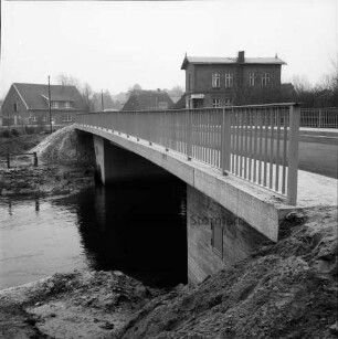 Trave: Brückenneubau: Spannbetonbrücke nach Fertigstellung: im Hintergrund Wohn- und Bauernhäuser: hinten rechts Gaststätte "Brückenkrug"
