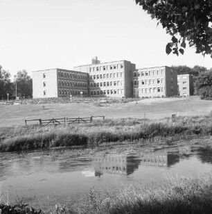 Trave: am gegenüberliegenden Ufer Wiesen, Zaun und Holzgatter: dahinter Kreiswehrersatzamt am Berliner Ring: hinten Bäume