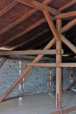 Am Markt (10): traufständiges Backsteingebäude mit umlaufendem Gesims: Innenansicht: Dachraum: Dach mit dreifach stehendem Stuhl: Blick auf Fußpfette, Mittelpfette, Kehlbalken, Innenständer, Dachsparren: hinten Außenwand, Schlitzfenster: unten Holzboden