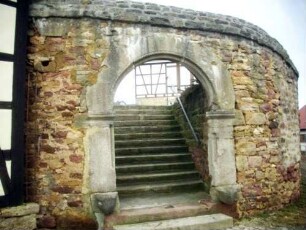 Kirchhofmauer im Südwesten (einstiger Wehrgang durch Regenabdeckung in Stein ersetzt) mit erhaltenem Torbogen (Außenbogen des einstigen Kammertors)