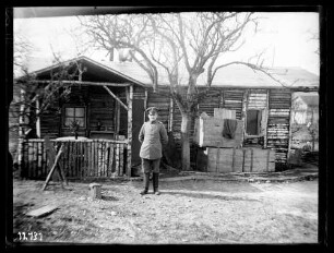 Offizier vor Unterkunft (einfaches Holzhaus)