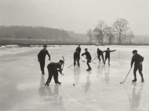 Acht Jungen beim Eishockeyspielen auf einem Teich