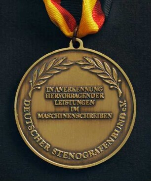 Bronzemedaille Deutsche Meisterschaften in Kurzschrift und Maschinenschreiben in Darmstadt 1986 am schwarz-rot-goldenen Band : Sammlung Deutscher Stenografenbund. Bronzemedaille Deutsche Meisterschaften in Kurzschrift und Maschinenschreiben in Darmstadt 1986 am schwarz-rot-goldenen Band. Messing, patiniert; Durchmesser 50 mm, Gewicht 39 g (1986; Deschler & Sohn, München). Dresden: SLUB R c 0544