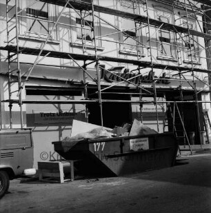 Bekleidungsgeschäft Knüppelholz: Besttorstraße: Umbau der Hausfront mit Gerüst: in den Fenstern Schilder: vorn Container für Bauschutt