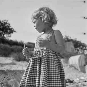 Kleines Mädchen mit Sonnebrille steht am Strand von Henkenhagen (heute: Ustronie Morskie)