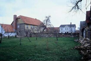 Kirchhof mit Blick zum Pfarrhaus; großenteils niedergelegte Kirchhofsmauer