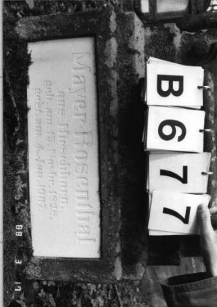 Grabstein 677 (Index: 99901927) Material: Sandstein und weiße Glasplatten Maße HxBxT: 162x53x25 cm Besonderheit: kulturhistorisch wertvoll / hist.-wiss. Gründe (Gemeindestellung): Grabstein 677B