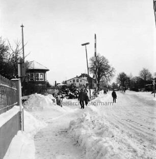 Bahnübergang Ratzeburger Straße: rechts und links Signalanlagen: links Streckenpostengebäude: in der Mitte auf Fußweg und auf Straße Fußgänger: hinten Mitte Wohnhäuser: Winter