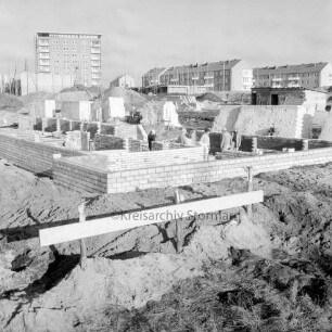 Greifswalder Kehre: Baustelle von Wohngebäuden, dahinter rechts Wohngebäude des Stonsdorfer Weges, links das Rathausgebäude, daneben der Kirchturm des Kirchliches Zentrums am Falkenberg: Blick nach Norden
