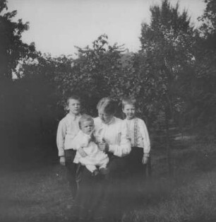 Mutter mit drei Kindern auf einer Wiese