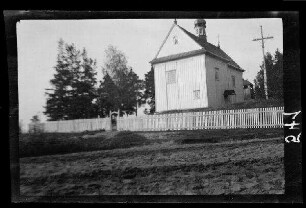 Rückansicht einer Holzkirche mit Umzäunung