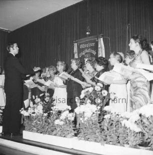 Oldesloer Singakademie von 1946: Oldesloer Hof: Saal: Festveranstaltung zum 25-jährigen Jubiläum: Gesangsvortrag des Chores: links Chorleiter: hinten Fahne: vorn Blumenschmuck: 26.09.1971