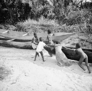 Kinder am Strand : Kinder spielen an Einbäumen am Strand von Bata.