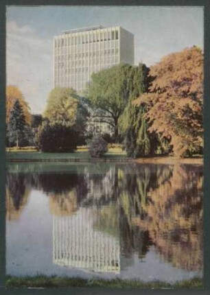 [Hochhaus, das sich im Wasser eines Sees davor spiegelt]