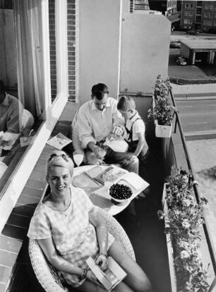 Model-Familie Keller befindet sich auf dem Balkon ihrer Wohnung Königstraße. Der Tisch zeugt von gesunder Lebensweise; Saft in Gläsern und Obst auf dem Tisch. Werbeaufnahme für die Techniker Krankenkasse (TK)
