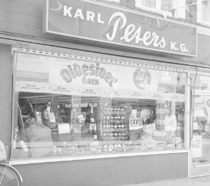 Peters Delikatessen: Mühlenstraße, Ecke Hindenburgstraße: Feinkostgeschäft: Außenaufnahme: Schaufenster: darin Dekoration zu 350 Jahre Bürgerschützengilde, Foto Karl Peters: darüber Firmenschild "Karl Peters K.G."
