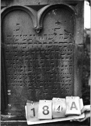 Grabstein 181 (Index: 99752035) Material: Sandstein Zustand: quer gebroch/repar. m. Textverl. /sonst gut Maße HxBxT: 168x52x17 cm Beschreibung: eingezog. Rundbogenabschl. m. Eckakroteren, Schriftfeld eingetieft m. zweibogigem Abs Symbolik: Ranken: Grabstein 181A