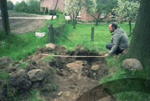 Bargfeld-Rögen: bei Elmenhorster Straße: Umsetzen von Meilenstein [Nr. 7]: alter Standort: Mann bei Vermessen von Ausbruchgrube