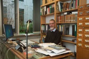 Porträt Perk Loesch, Fachreferent der SLUB : Porträt des Kunstwissenschaftlers Perk Loesch, Fachreferent und von 1996 bis 2019 Leiter der Handschriftenabteilung an der Sächsischen Landesbibliothek – Staats- und Universitätsbibliothek Dresden (SLUB). Aufnahme an seinem Schreibtisch