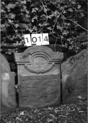 Grabstein 1014 (Index: 99630517) Material: Sandstein Zustand: stark verwittert Maße HxBxT: 61x47x9 cm Beschreibung: Stele mit eingezogenem Segmentbogenabschluß Symbolik: Girlande: Grabstein 1014
