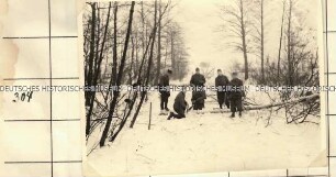 Angehörige der Ordnungspolizei beim Fällen eines Baumes in einem verschneiten Waldstück