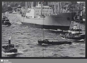 Einlaufendes Frachtschiff wird zum Liegeplatz geschleppt